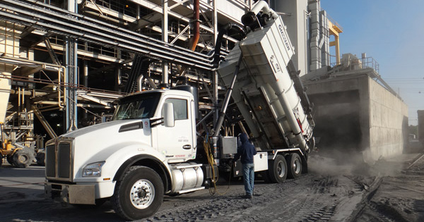 Vacuum truck pouring material from silo cleaning